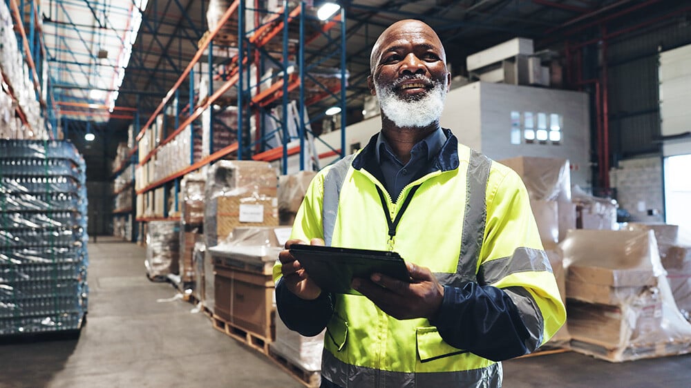Smiling warehouse employee with a tablet